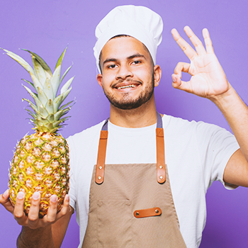 A person holding up a pineapple with an okay sign on his other hand