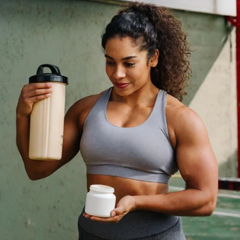 A woman holding a pre-workout drink and a fat burner