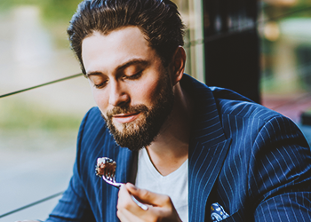 A handsome man eating cooked steak in a restaurant