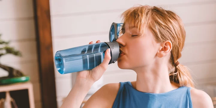 A woman in a gym drinking water