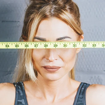 A woman holding a measuring tape to her face