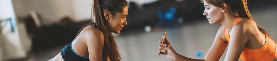 Two women in the gym looking at a phone screen