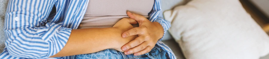 A woman holding her groin on a couch