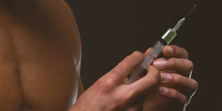 A muscular man holding injectable steroids