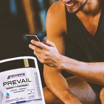 A person in the gym looking at his phone with Prevail Pre-workout in the foreground