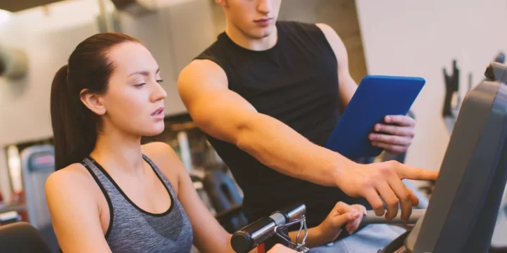 Two people in the gym discussing at a treadmill