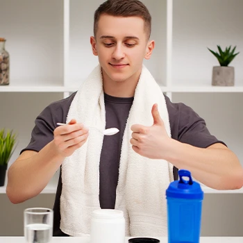 Giving a thumbs up while holding a spoon with pre workout supplement