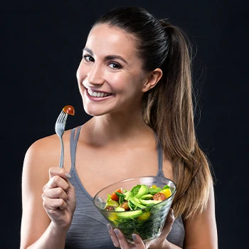 A woman smiling while eating healthy vegetable meal