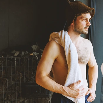 A man in a sauna looking outside a window