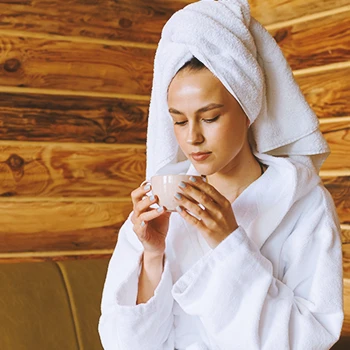 A woman drinking tea inside a sauna