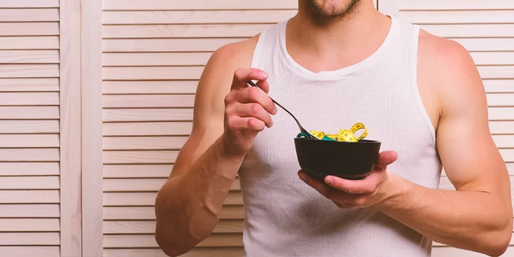 A buff person holding a bowl of measuring tape