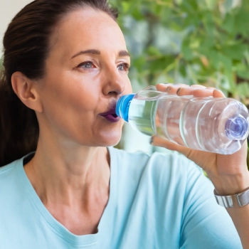 Middle aged woman drinking on a bottled water