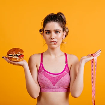 A woman holding a burger and a measuring tape