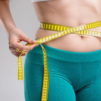 Close up shot of a person's belly with a measuring tape