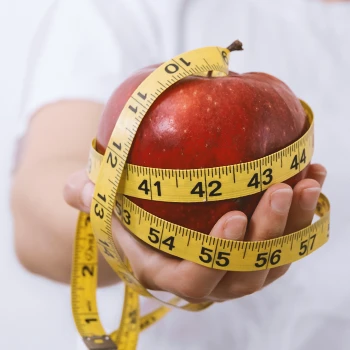 An apple with a measuring tape wrapped around it