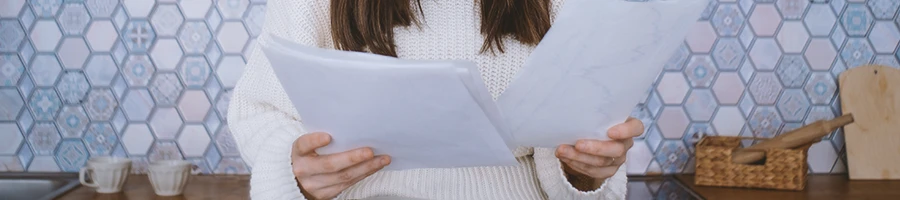 A person looking at papers inside a kitchen