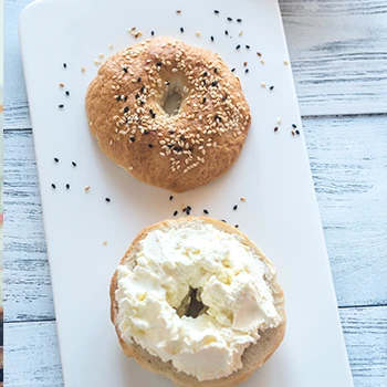 Plain Bagel with low fat cream cheese on top of a white board