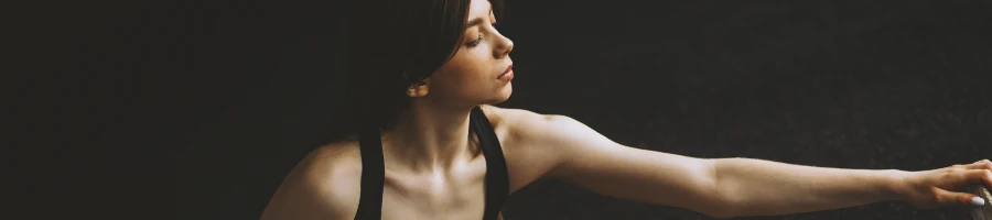 A fit woman stretching in a dark room