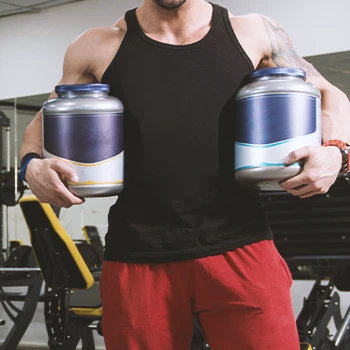 A buff male holding supplements in the gym