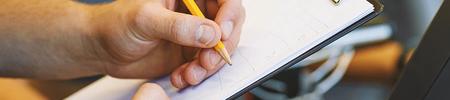 A gym coach writing down on a clipboard