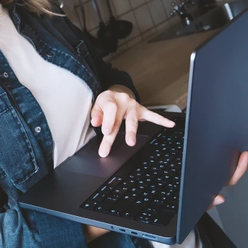 A woman holding a laptop in the kitchen