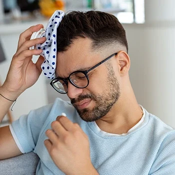 A young man experiencing a headache while holding a medicine