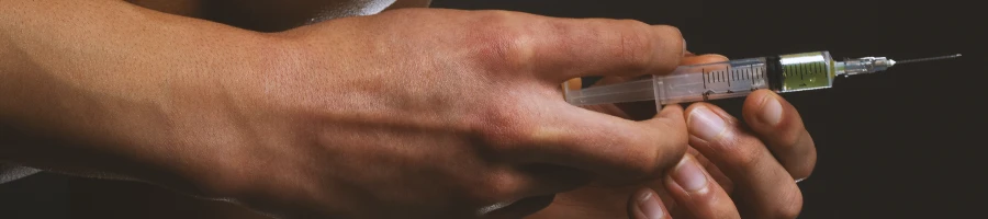 Close up shot of a person's hand holding a syringe