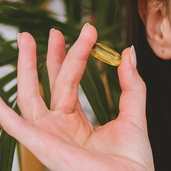 A person holding a pill of Vitamin E