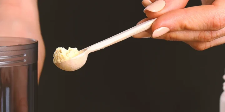 A person scooping a tiny amount of protein powder