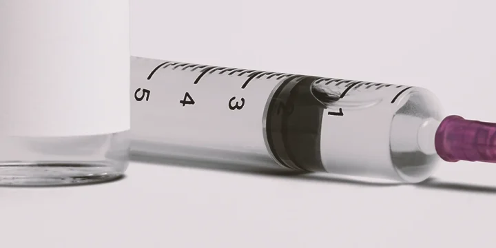 Close up shot of a syringe on a white table