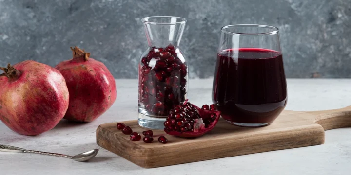 A jar full of Pomegranate juice and fruit beside