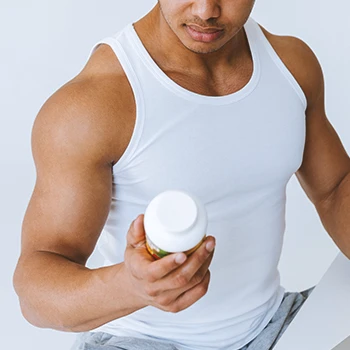 A buff male holding a bottle of Saw Palmetto pills