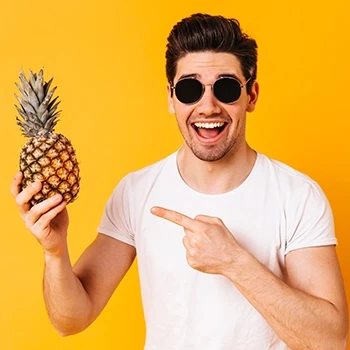 A joyful person holding a pineapple to boost his testosterone