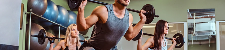 A group doing barbell squats in gym