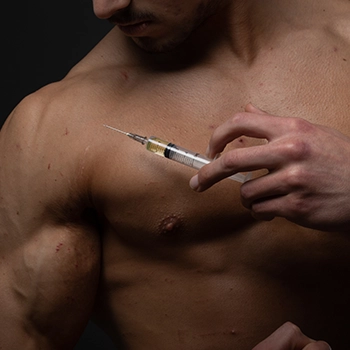 A muscular person holding a syringe to inject to his body