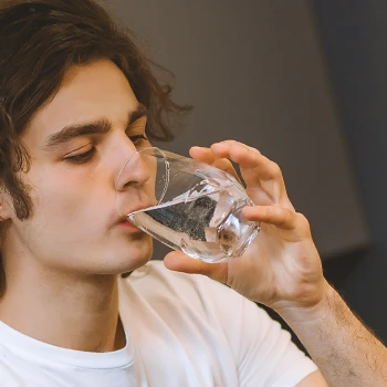 A person drinking water inside the kitchen