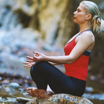 A woman doing yoga outside in the forest