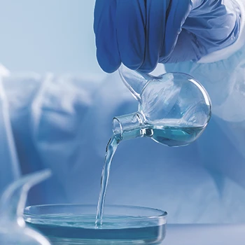 A scientist pouring a chemical on a dish