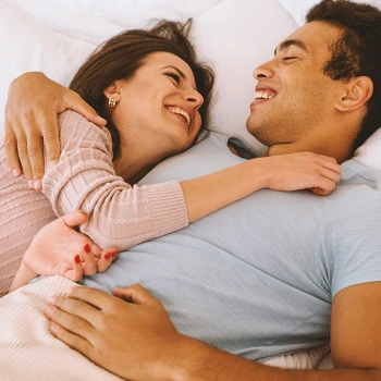 A couple happy in bed smiling at each other