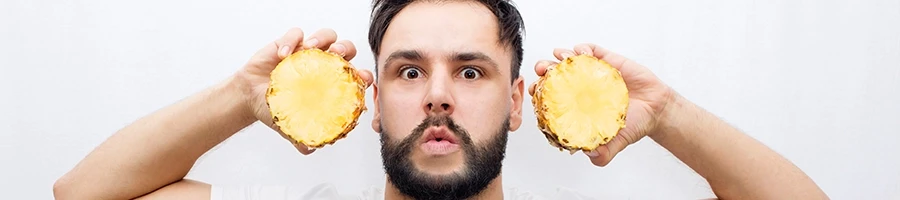 Man holding two slices of pineapple