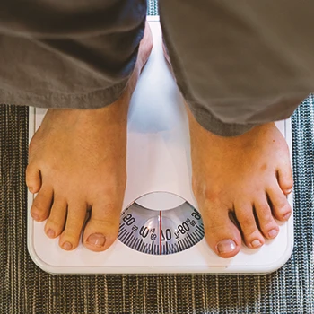 A woman measuring her weight on a weighing scale