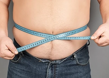 Man holding tape measure around his belly