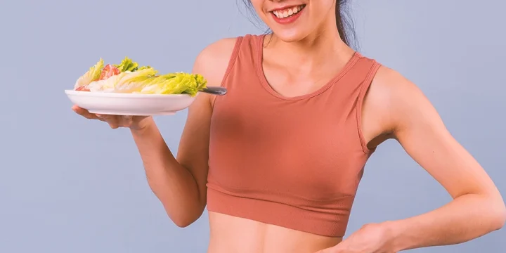 A woman holding a plate of vegetables that burn the most fat