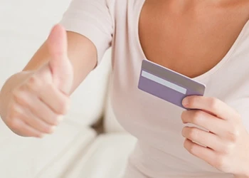 Woman holding credit card giving thumbs up