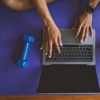 Top view of a person using a laptop with weights on the side