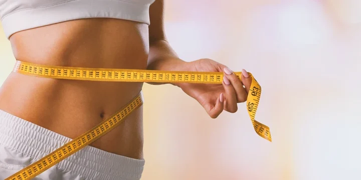 A woman with a measuring tape around her stomach