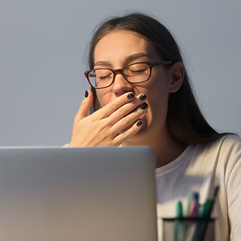 Drowsy woman yawning while working in front of laptop
