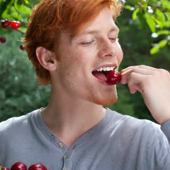 A person eating a cherry outside
