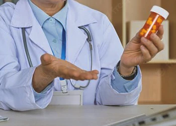 A doctor reading the label of a pill bottle