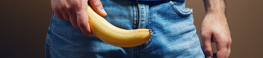 Holding long banana in front of pants